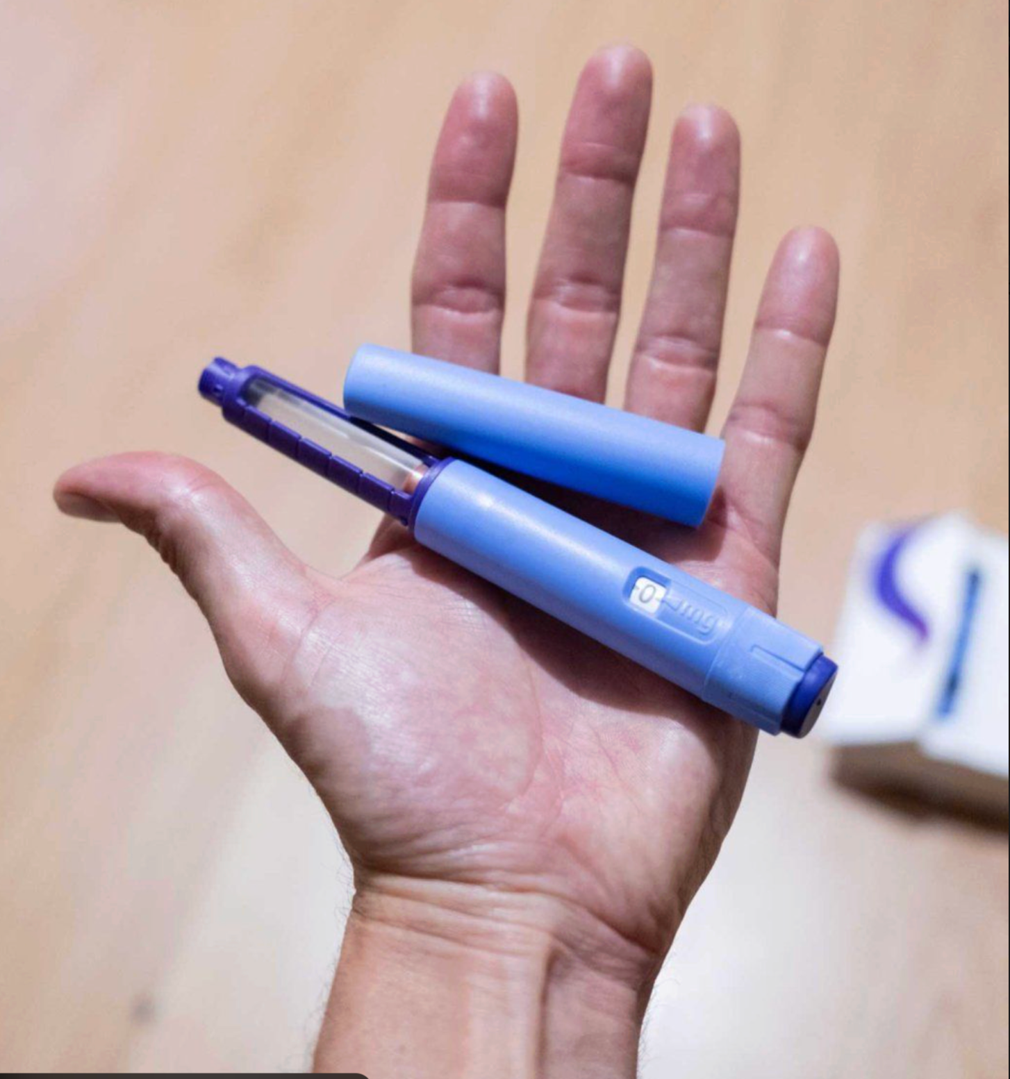 GLP-1 weight loss injection pen held in hand against neutral background
