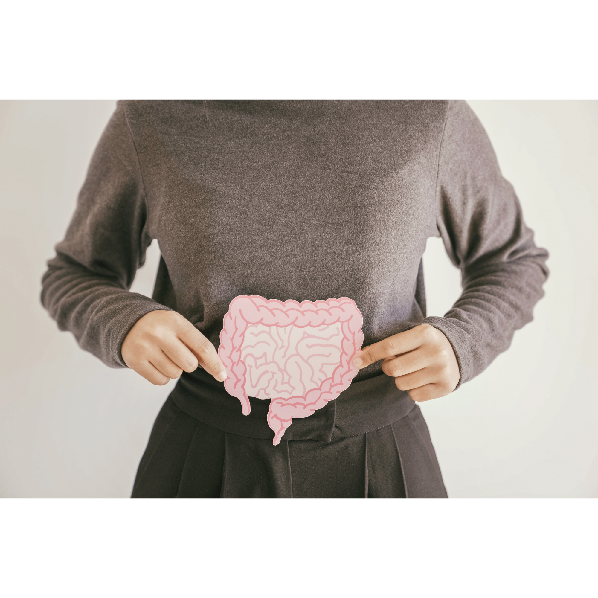 Person holding illustrated gut graphic over abdomen to represent gut health and digestion
