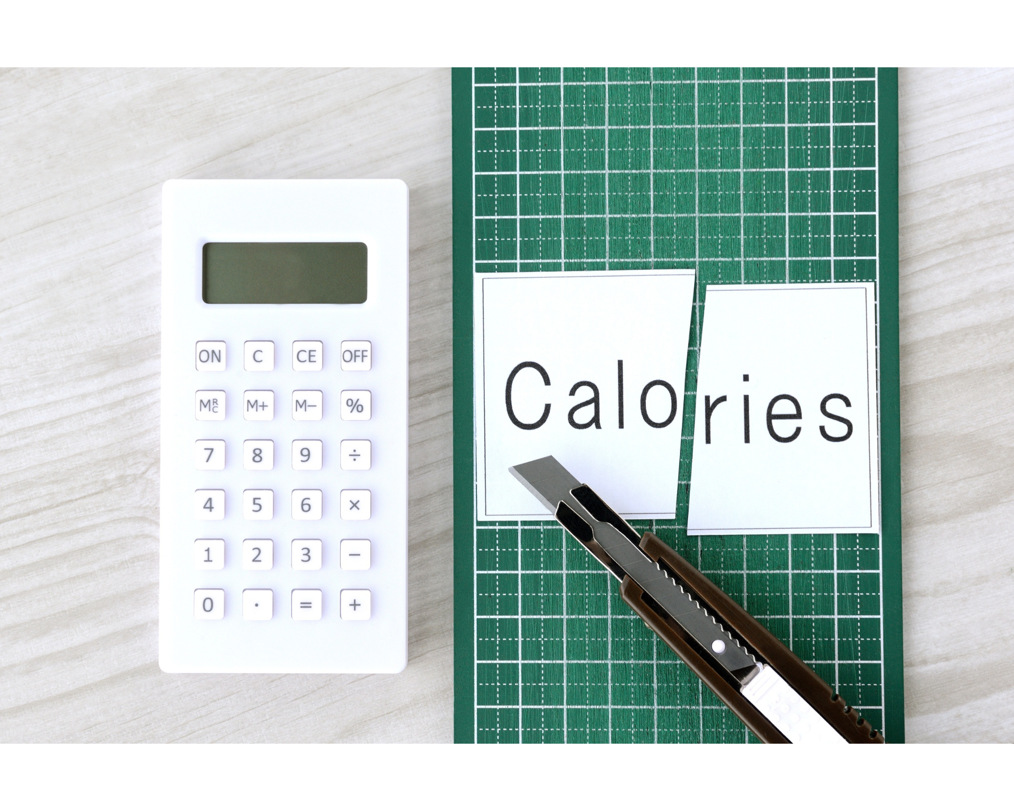 Calculator and cut-out calories text representing calorie deficit and weight loss tracking