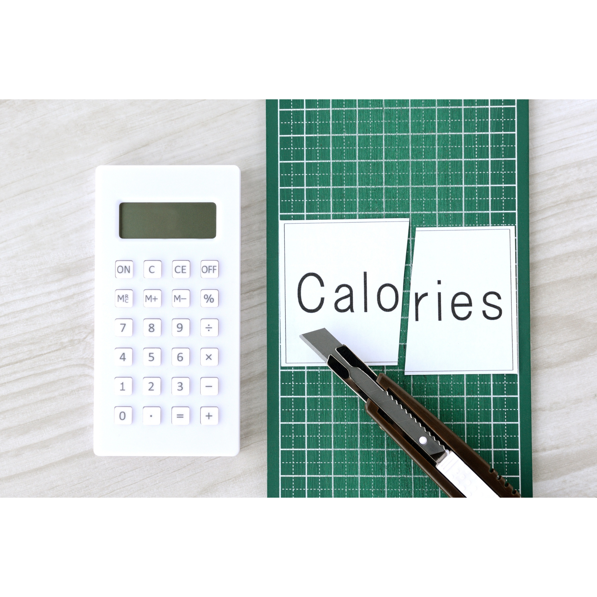 Calculator and cut-out calories text representing calorie deficit and weight loss tracking